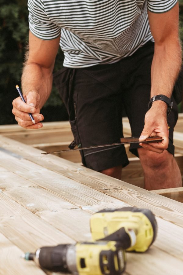 Man at BOP Fence measures a sheet of timber to be cut